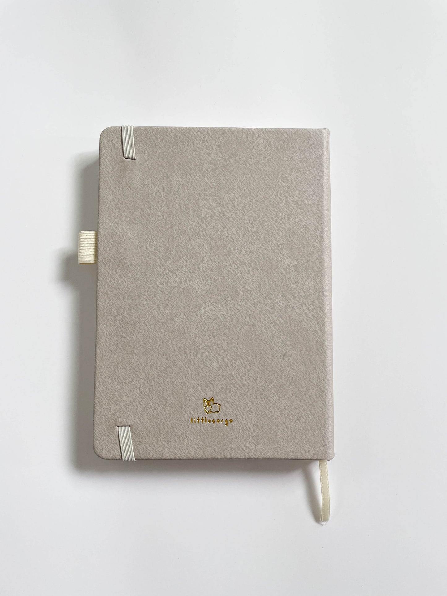 The back side of an ivory bullet journal that has a gold foil embossed design at the bottom.