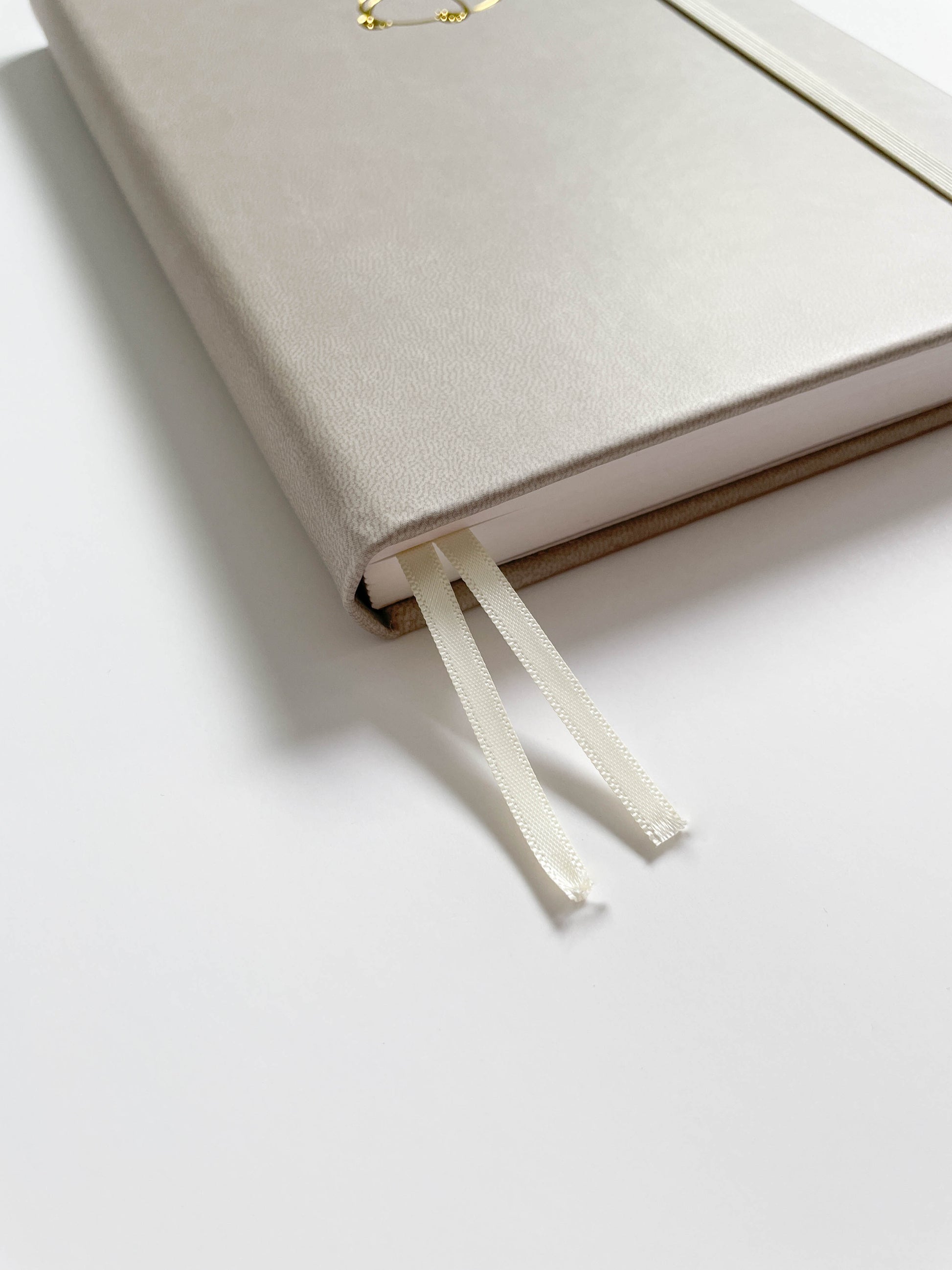Bottom view of an ivory bullet journal that shows two white fabric bookmarks.